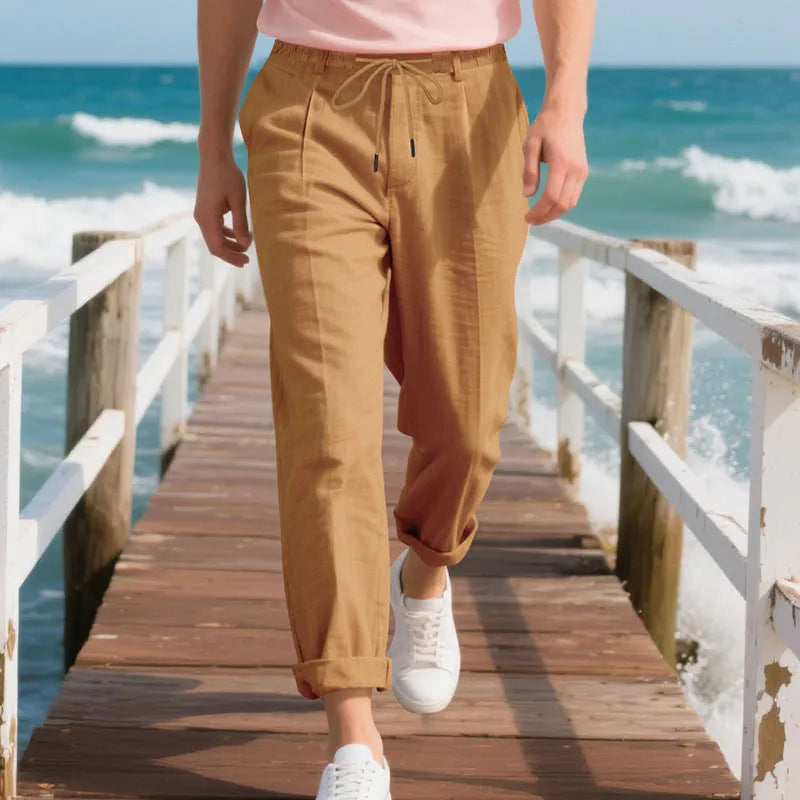 Men's light beige linen trousers with a loose straight leg and drawstring waist on a hanger.