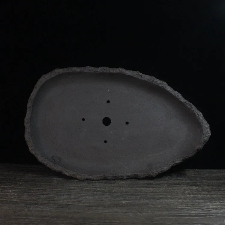 Handmade purple clay flower pot with unique shape showing natural ceramic texture
