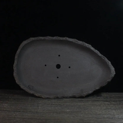 Handmade purple clay flower pot with unique shape showing natural ceramic texture
