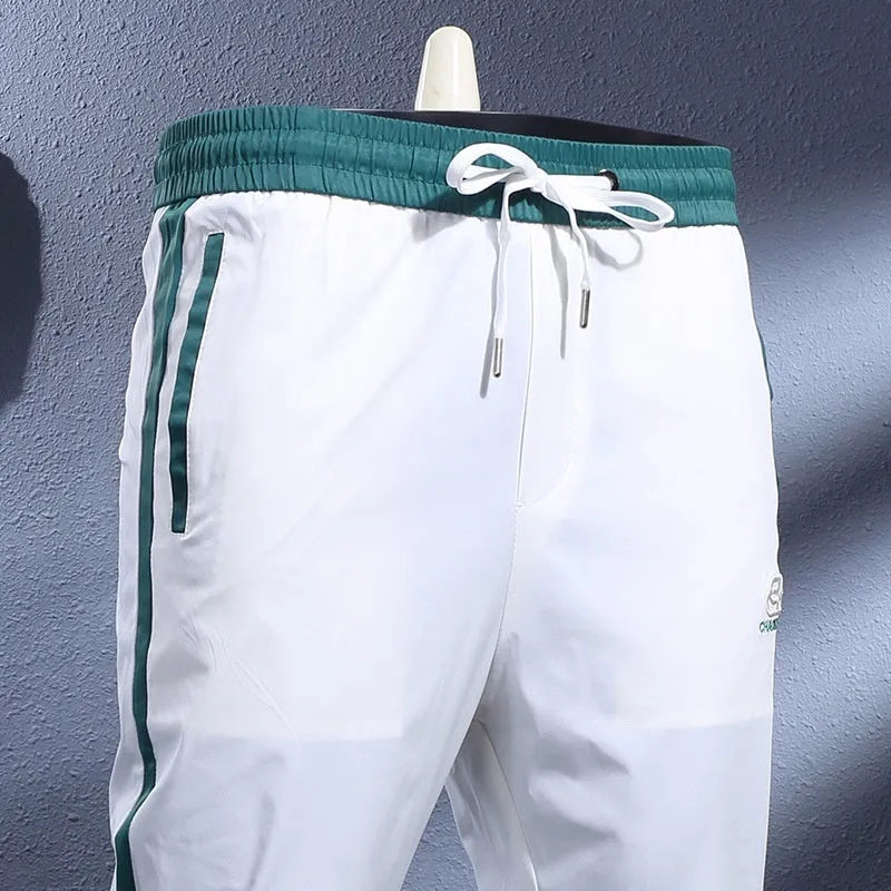 Men's ice silk skinny sports pants in black or white with striped tapered leg and ankle-tied hem