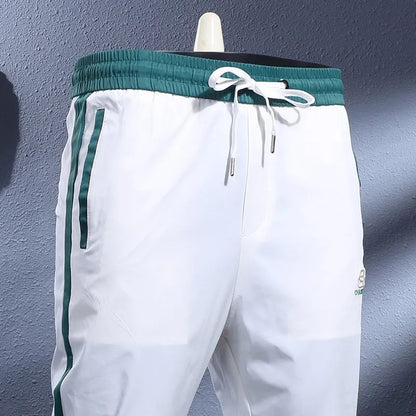 Men's ice silk skinny sports pants in black or white with striped tapered leg and ankle-tied hem