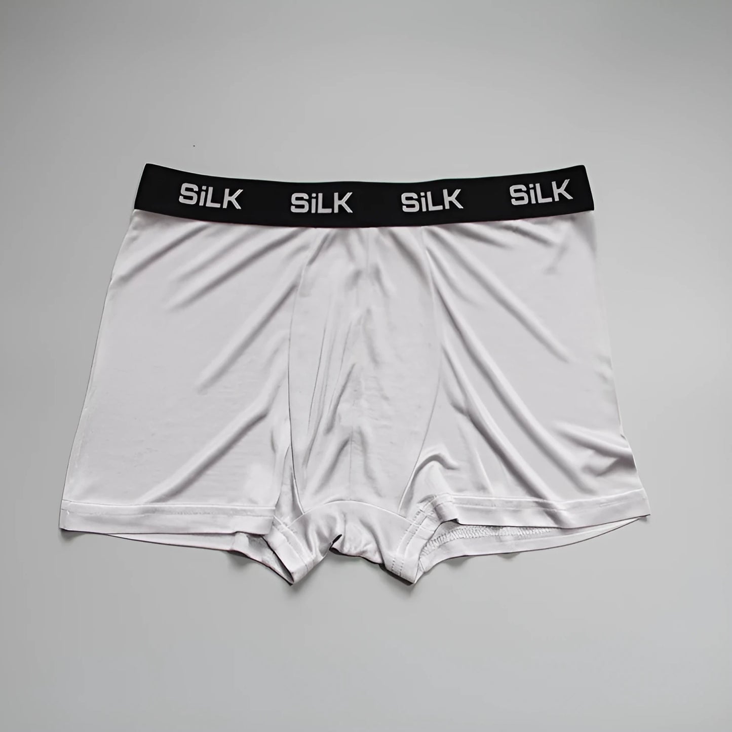 Men's loose-fitting silk shorts in navy blue on a neutral background.