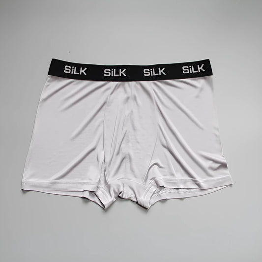 Men's loose-fitting silk shorts in navy blue on a neutral background.