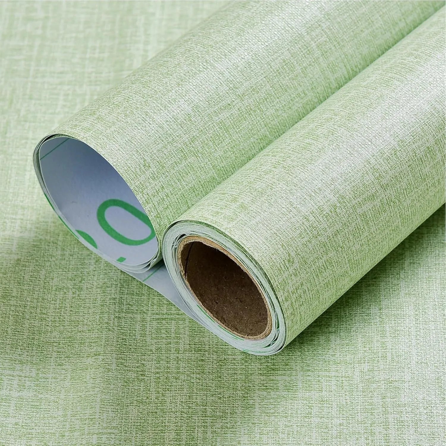 Close-up of linen-textured self-adhesive wallpaper roll in beige colour, showing peel-off backing.