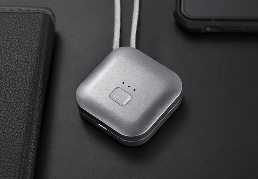 Pink wearable USB air purifier necklace on a table with USB cable, showing compact size.