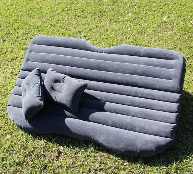 Black inflatable car bed with flocked surface and two pillows, shown folded into a chair inside a vehicle.