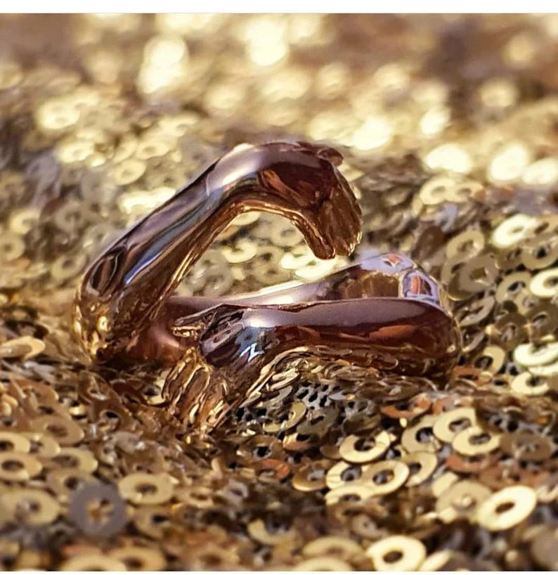 Adjustable geometric love hands embracing ring in gold and silver, perfect for gifts.