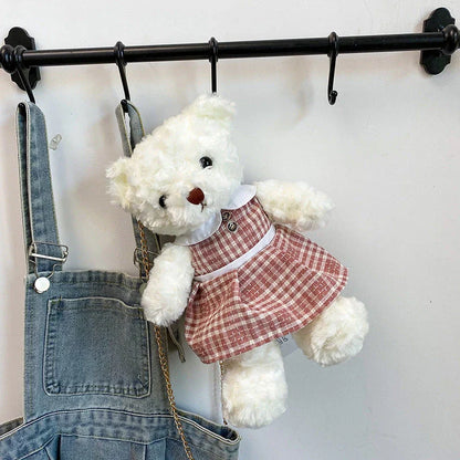 A plush teddy bear crossbody messenger bag with an adjustable shoulder strap and a zippered interior pocket for convenient storage.