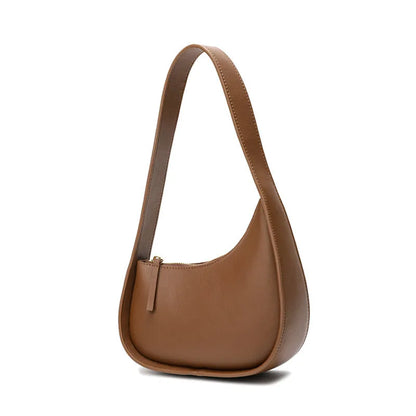 Structured caramel half-moon leather women's shoulder bag with a wide adjustable strap and zip closure.