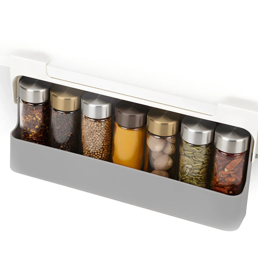 White plastic hanging spice rack with six clear glass bottles, mounted on kitchen door for punch-free storage