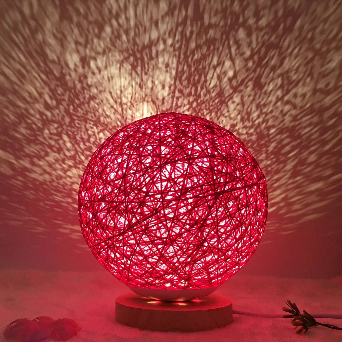 Spherical hand-knitted rattan table lamp with remote control on a wooden desk