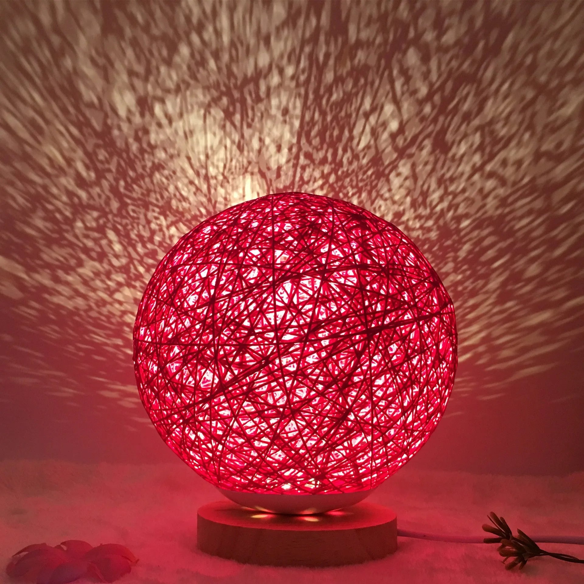 Spherical hand-knitted rattan table lamp with remote control on a wooden desk