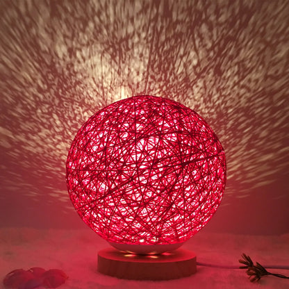 Spherical hand-knitted rattan table lamp with remote control on a wooden desk