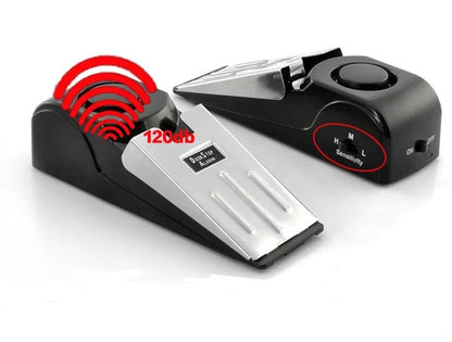 Portable wedge-shaped door stop alarm unit with stainless steel cover and sensitivity controls.