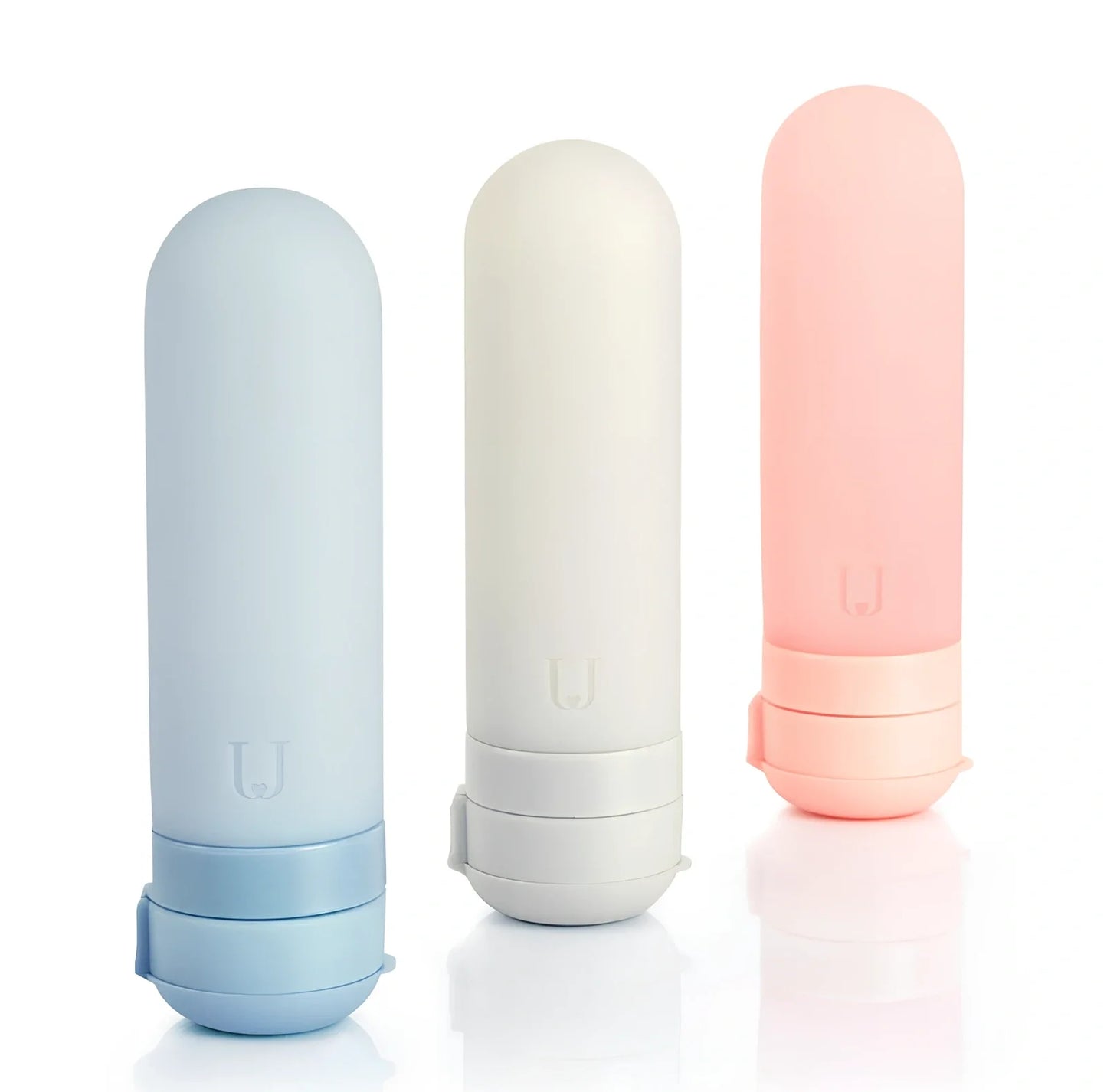 Set of three silicone travel bottles in light grey, pink, and blue colours with screw caps