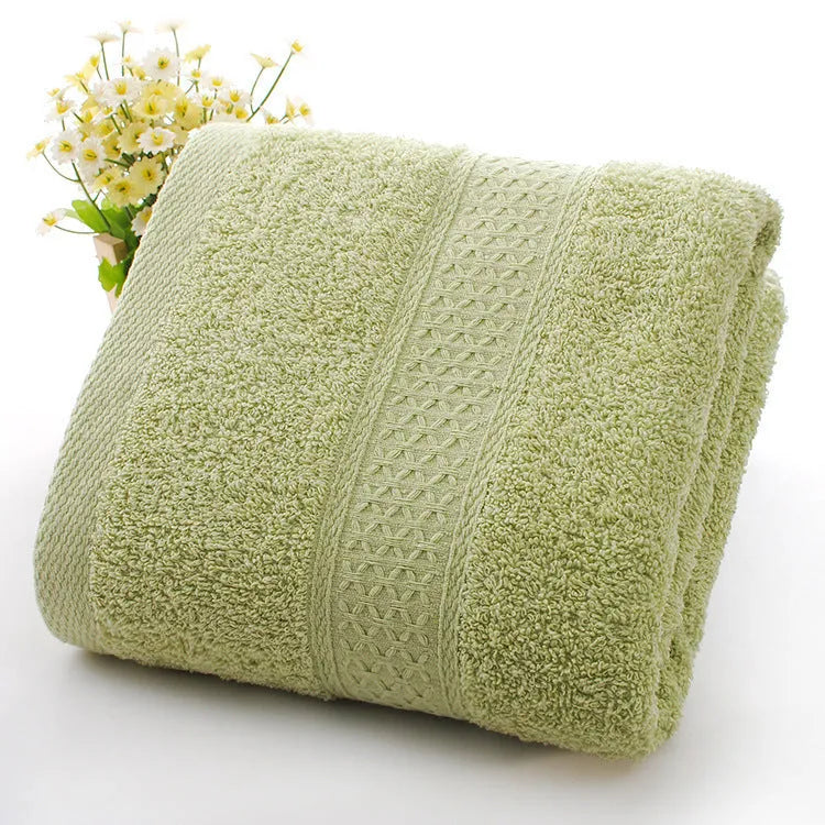 A stack of thickened cotton bath and beach towels in various colours including apple green, dark blue, and light pink.