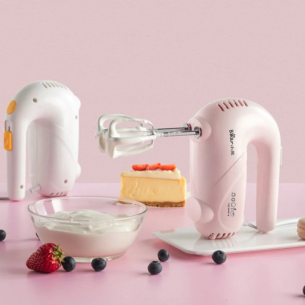 Pink electric hand whisk with stainless steel attachments for whipping eggs and cream