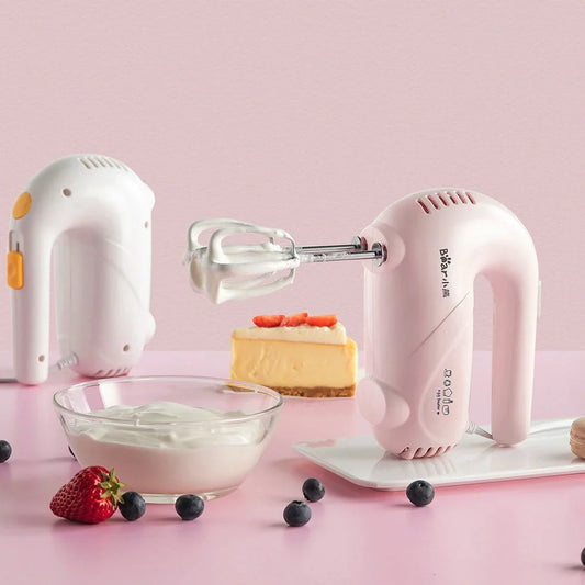 Pink electric hand whisk with stainless steel attachments for whipping eggs and cream
