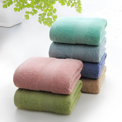 A stack of thickened cotton bath and beach towels in various colours including apple green, dark blue, and light pink.