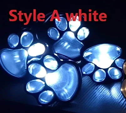 Four black paw-shaped solar garden lights with connecting wire and central solar panel for automatic outdoor illumination