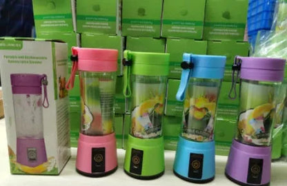 Compact pink portable blender with USB charging cable and box, shown alongside blended fruit smoothie.
