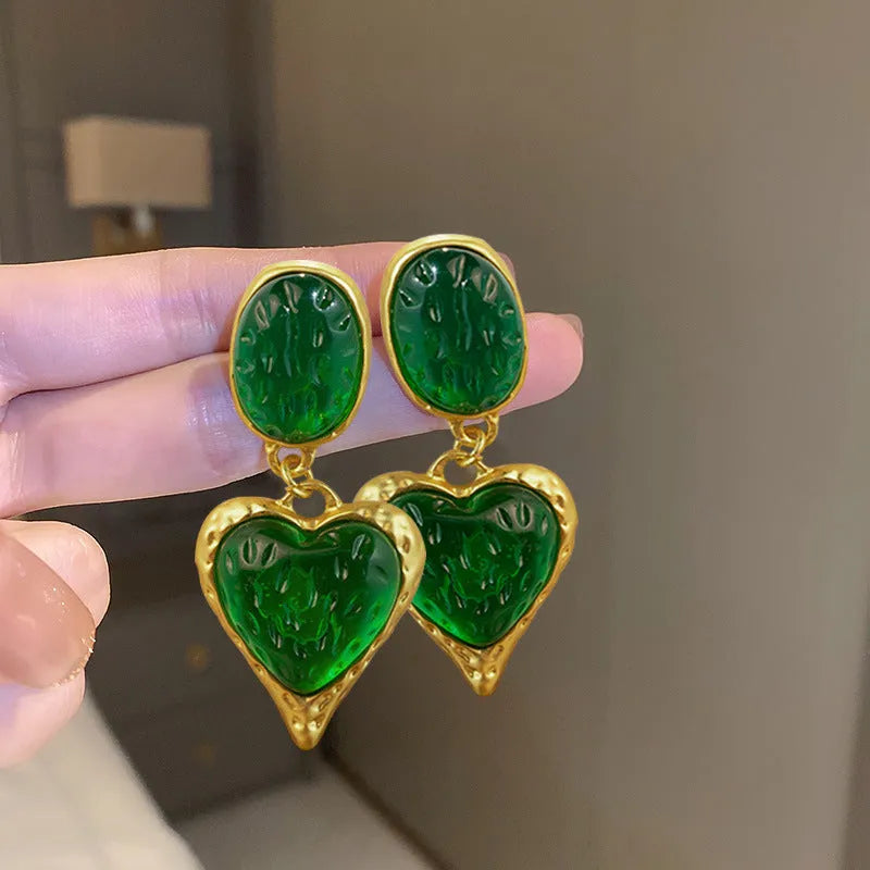 A pair of silver-tone stud earrings with a textured pleated oval love heart shape in various colour options.