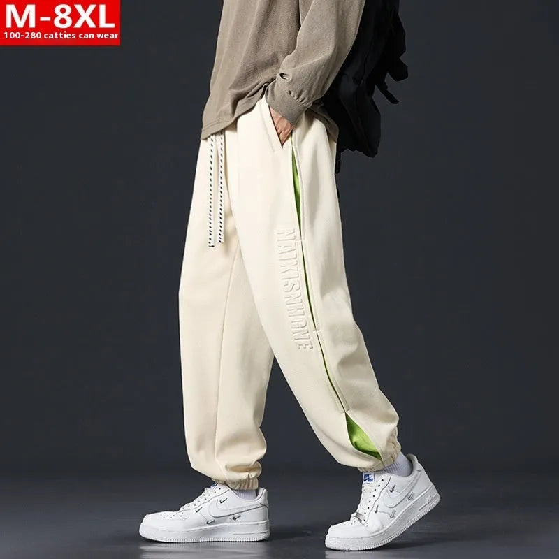 Men's ankle banded trousers in micro-elastic cotton with collage stitching details, showing loose fit and tapered leg
