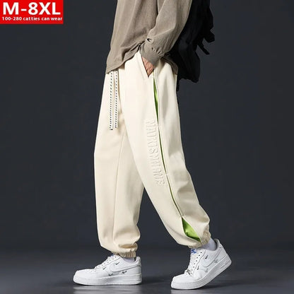 Men's ankle banded trousers in micro-elastic cotton with collage stitching details, showing loose fit and tapered leg