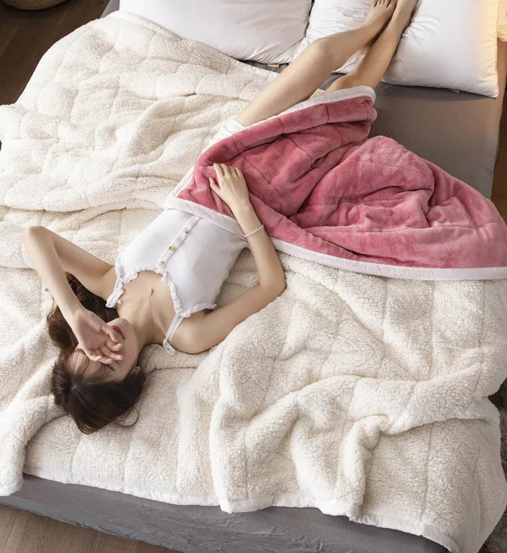Thick pink coral fleece blanket folded on a twin bed.