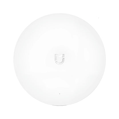 White circular Xiaomijia smart home gateway with UK plug on a wall.