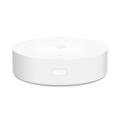 White circular Xiaomijia smart home gateway with UK plug on a wall.