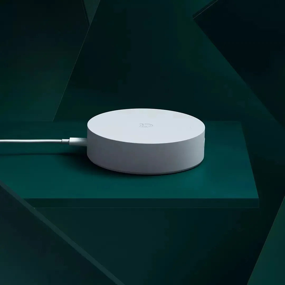 White circular Xiaomijia smart home gateway with UK plug on a wall.