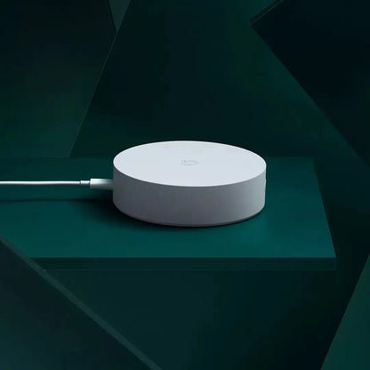 White circular Xiaomijia smart home gateway with UK plug on a wall.