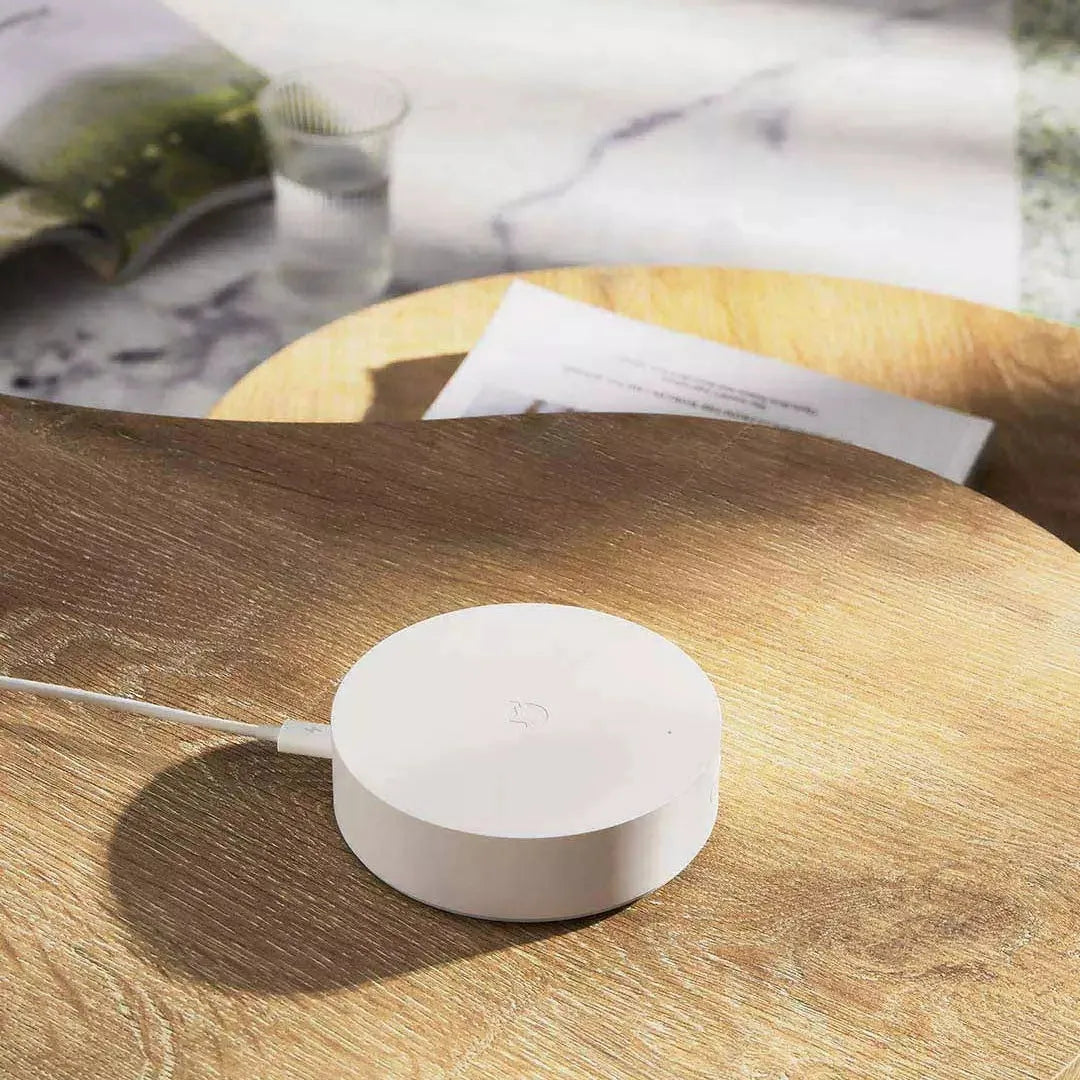 White circular Xiaomijia smart home gateway with UK plug on a wall.