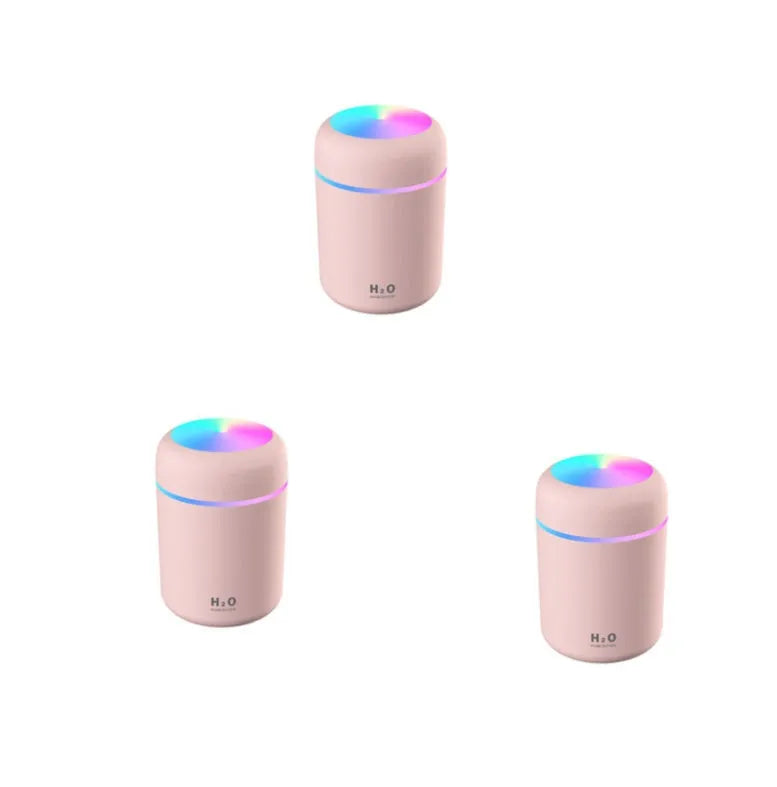 Pink car air purifying humidifier with LED lights on, next to a USB cable.