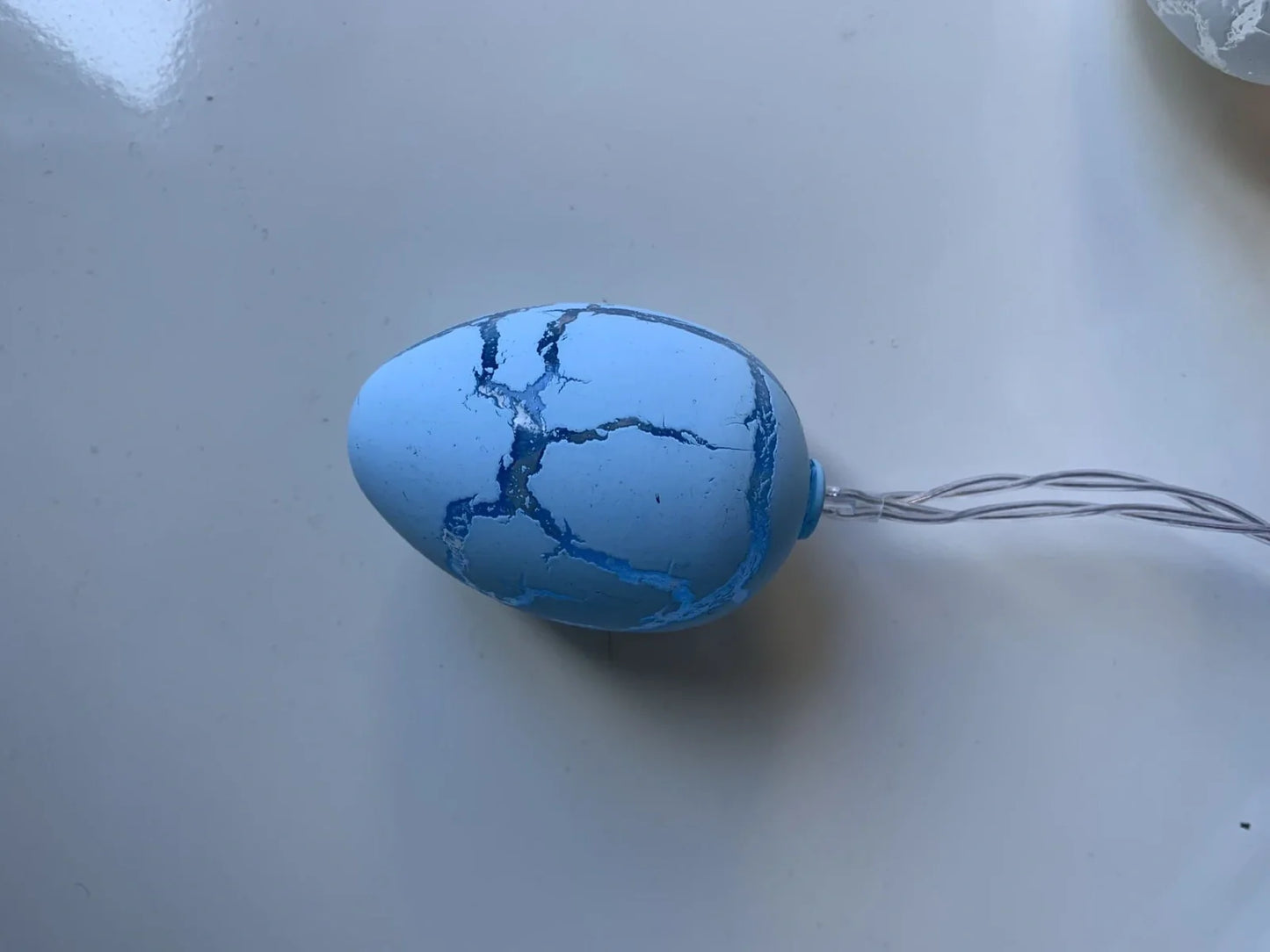 Crack egg LED string lights shaped around window with coloured plastic shells and flexible cable