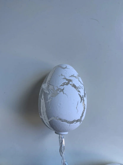 Crack egg LED string lights shaped around window with coloured plastic shells and flexible cable