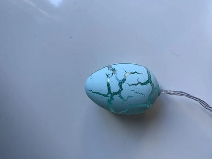 Crack egg LED string lights shaped around window with coloured plastic shells and flexible cable
