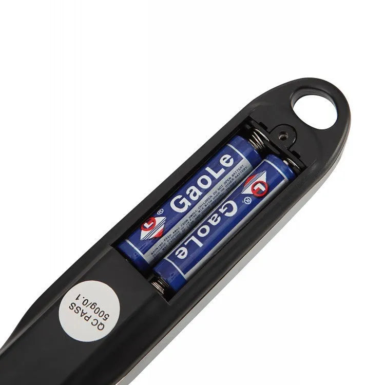 Smart digital measuring spoon with electronic display showing weight, alongside two AAA batteries.
