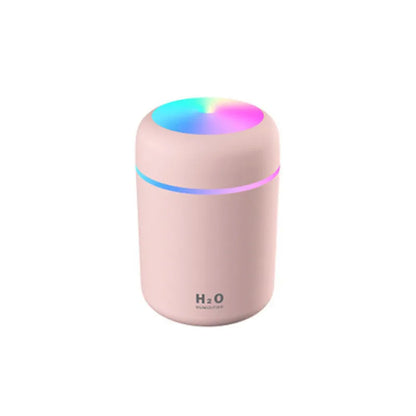 Pink car air purifying humidifier with LED lights on, next to a USB cable.