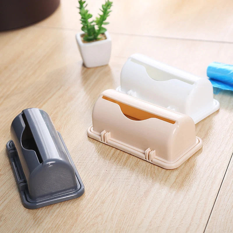 Wall-mounted plastic trash bag dispenser in white, grey, and pink for kitchen organization