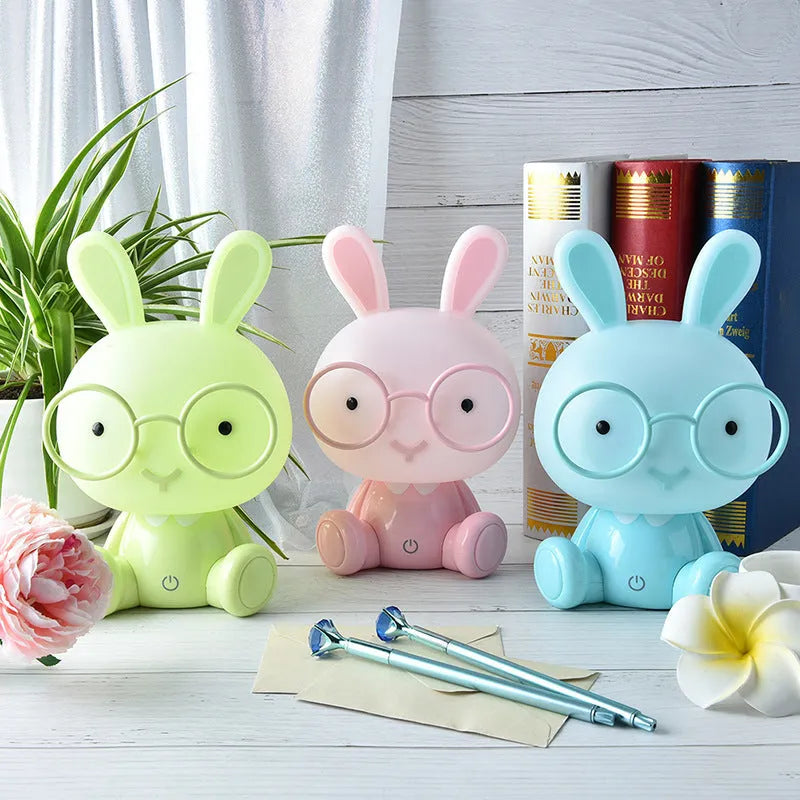 USB cartoon rabbit night light with glasses, in blue, green, or pink colour options on a table