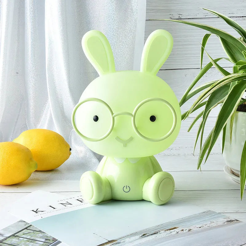 USB cartoon rabbit night light with glasses, in blue, green, or pink colour options on a table