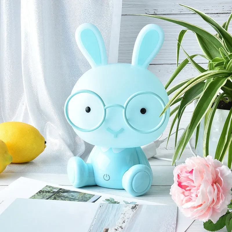 USB cartoon rabbit night light with glasses, in blue, green, or pink colour options on a table