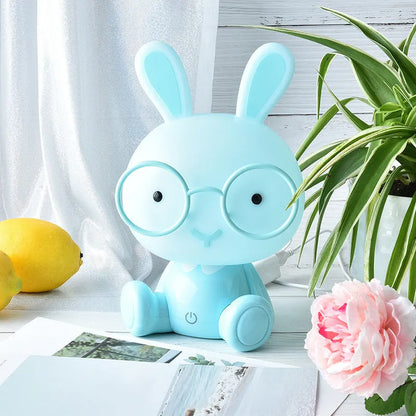 USB cartoon rabbit night light with glasses, in blue, green, or pink colour options on a table
