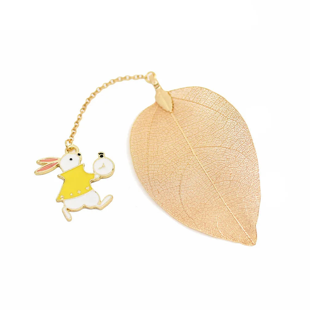 KC alloy metal bookmark with leaf, Alice, rabbit, and clock charms on an open book.