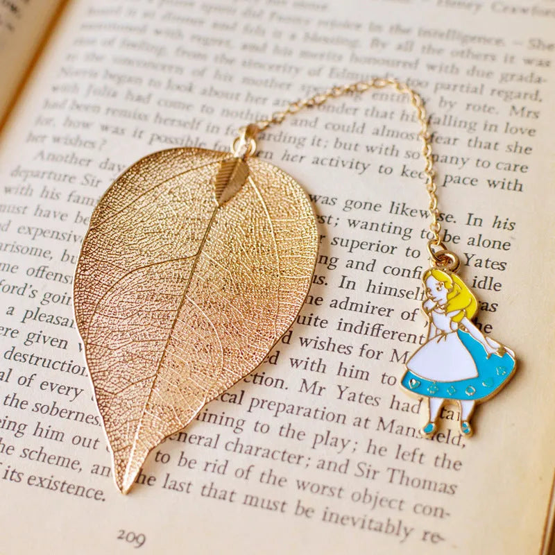 KC alloy metal bookmark with leaf, Alice, rabbit, and clock charms on an open book.