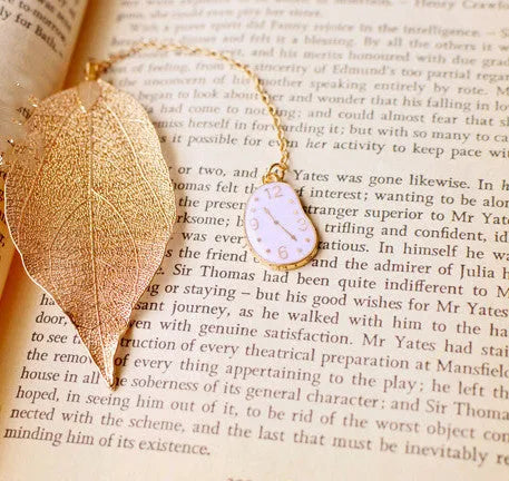 KC alloy metal bookmark with leaf, Alice, rabbit, and clock charms on an open book.