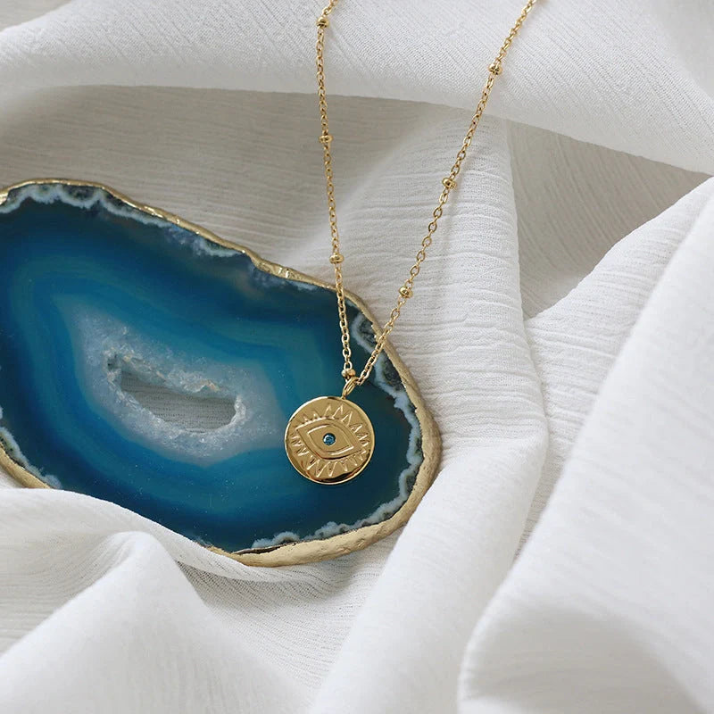 Mesmerizing blue-eyed gold coin pendant necklace with titanium steel chain and Seiko processing for premium quality and style
