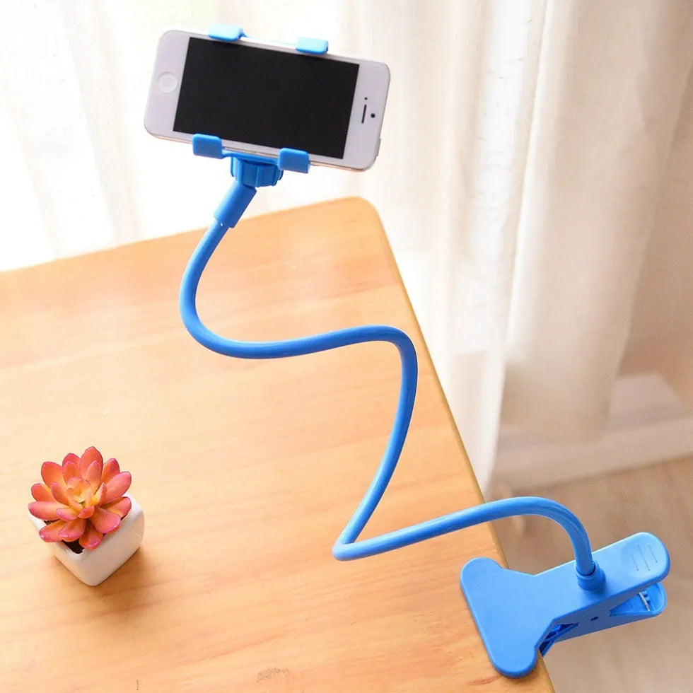 Black flexible arm mobile phone holder with V-clip gripping a smartphone, extended to 70cm on a bedside table.